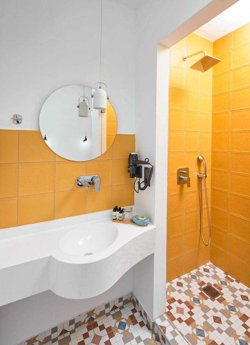 Bagno con piastrelle senape e doccia a motivi in terracotta