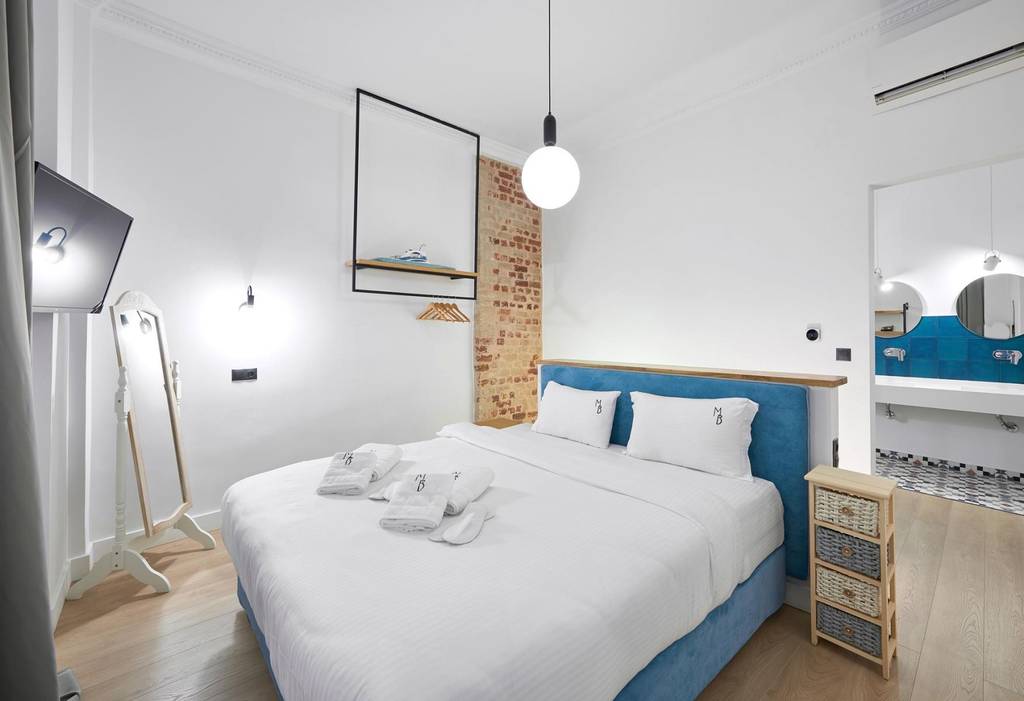 Bedroom with teal headboard and exposed brick accent wall