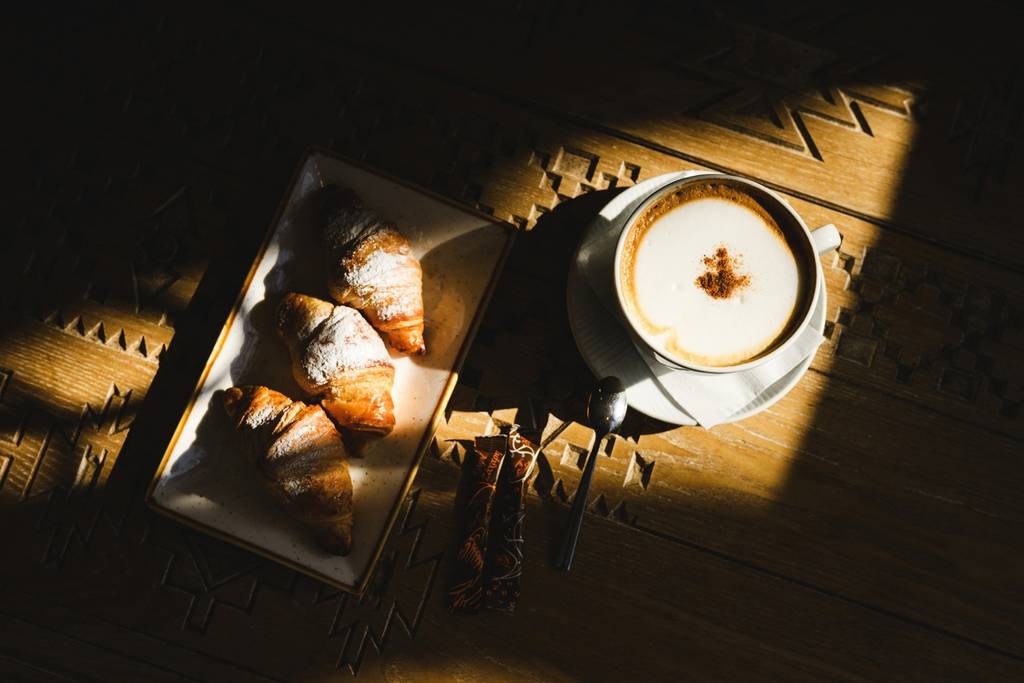 Powdered croissants and cappuccino on a carved wooden table