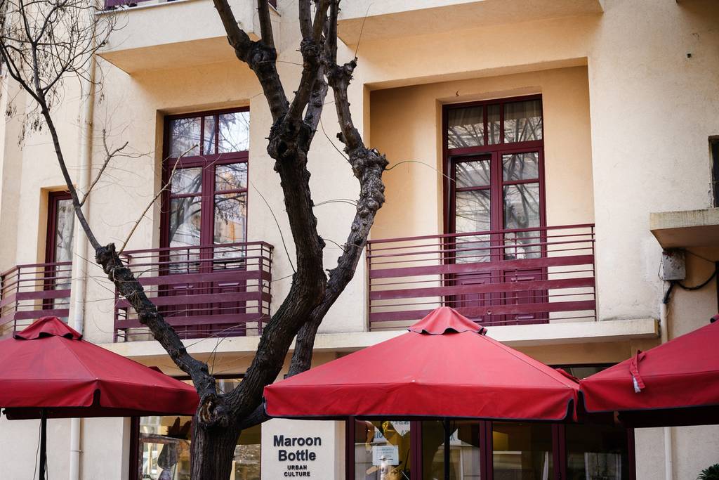 Hotel facade with maroon balconies and red umbrellas