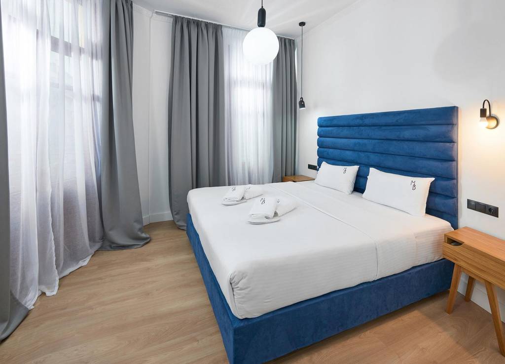 Double room with navy velvet headboard and grey curtains