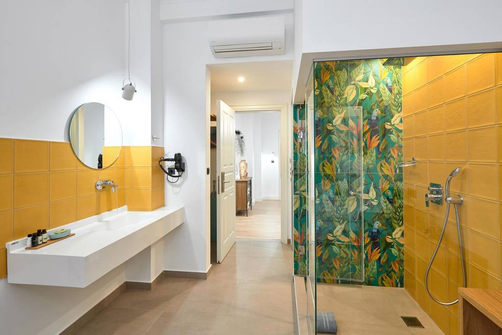 Bathroom with mustard tiles and tropical parrot mosaic shower